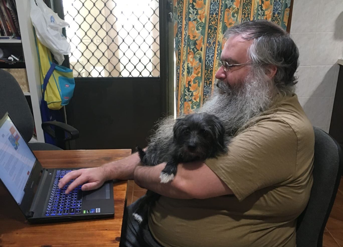 A man working from home with a dog on his lap