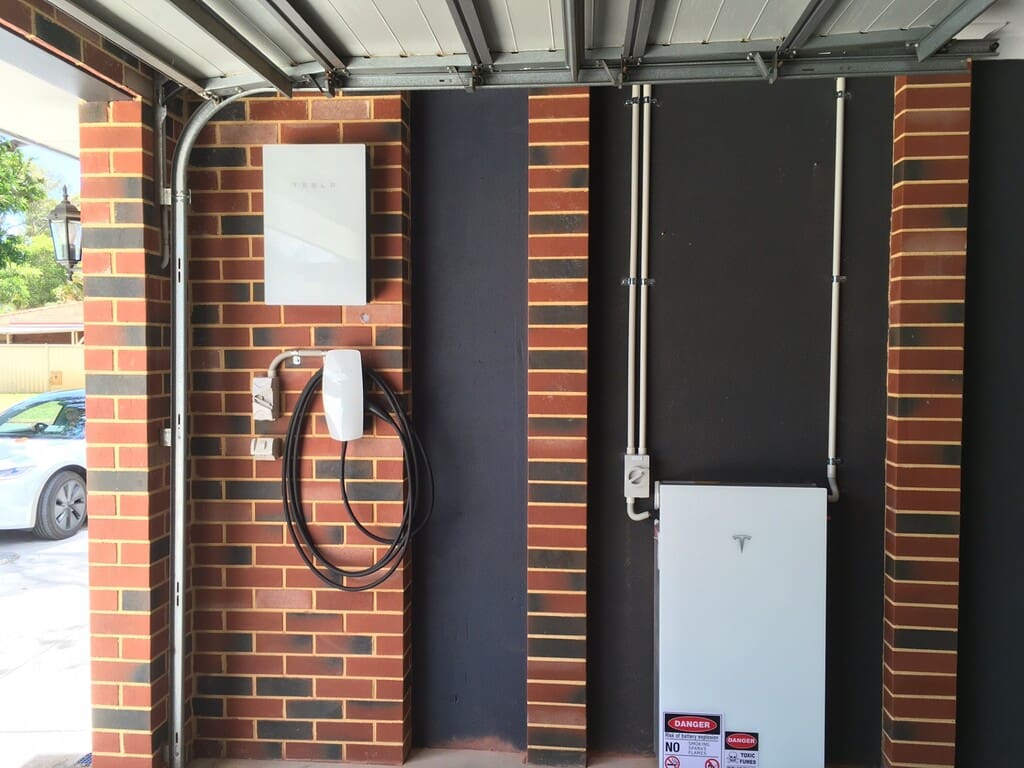 A Powerwall battery against a brick wall