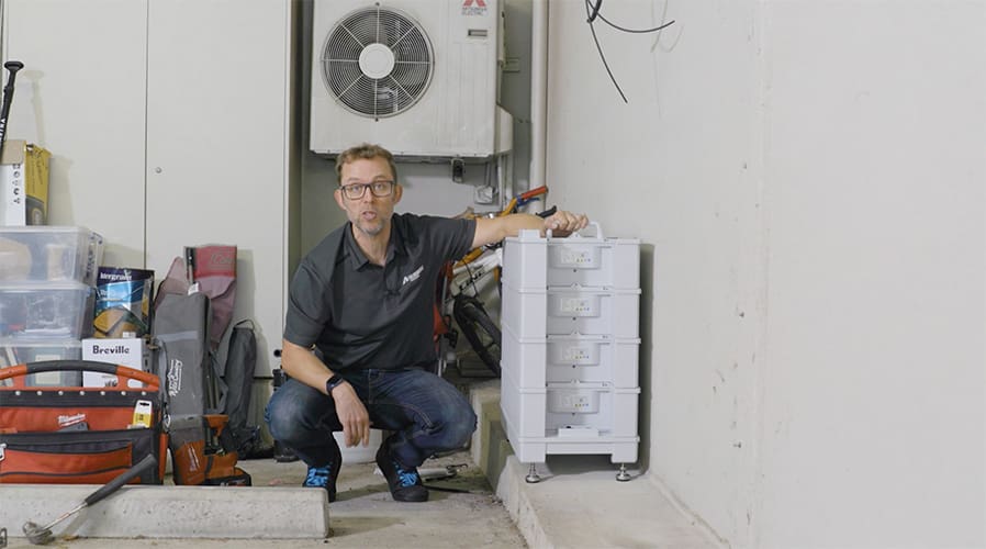A man crouches next to a Sungrow battery