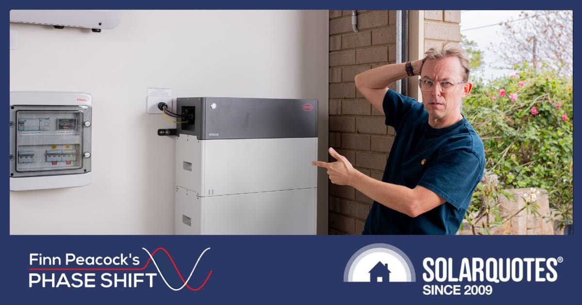 SolarQuotes founder finn Peacock clutches his head and points at a home battery system
