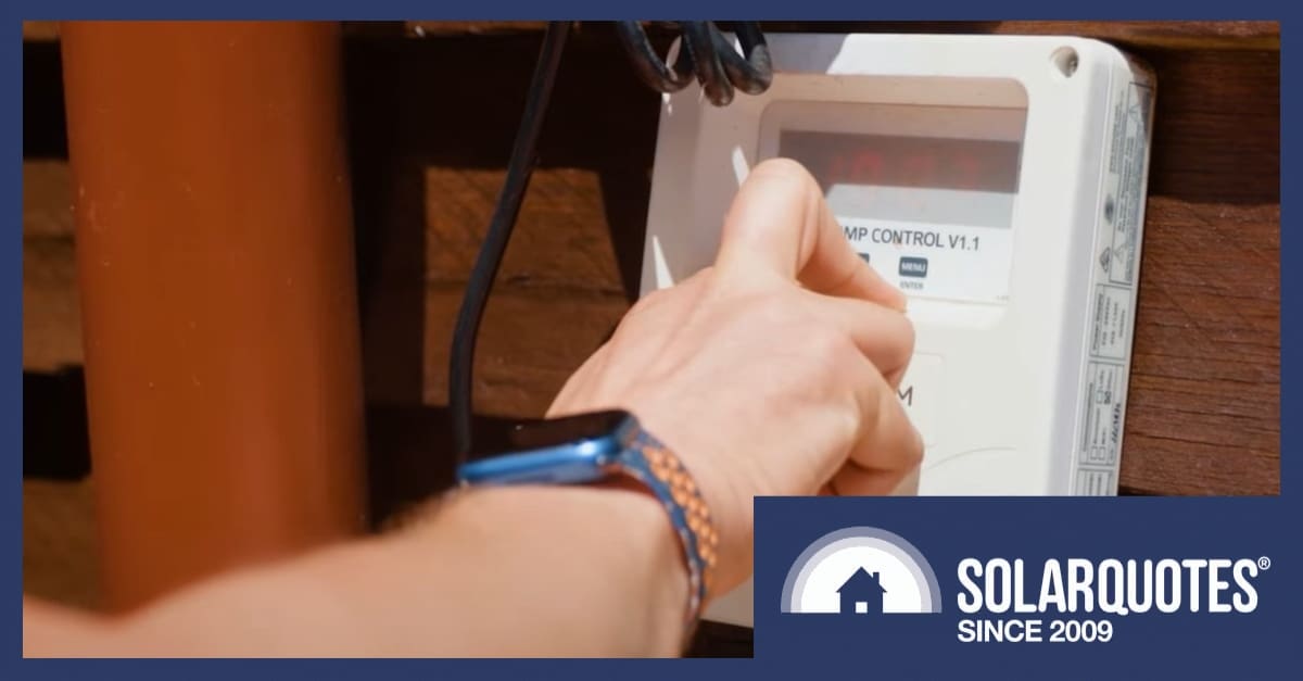 A hand turning a hot water heat pump timer