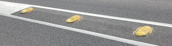 Little yellow speed bumps on a road.