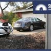 Two EVs charging in a driveway with an EV charger on the garage.