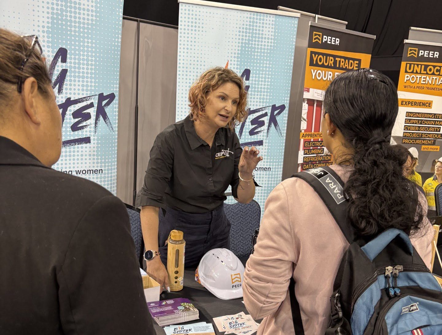 Women speaking at a booth at a jobs exhibition.