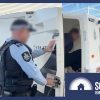 A man getting hauled into a paddy wagon.