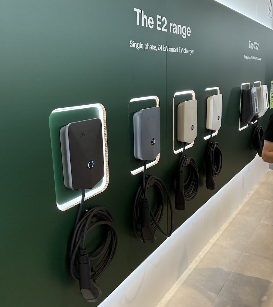 Evnex EV chargers lined up on a green wall.