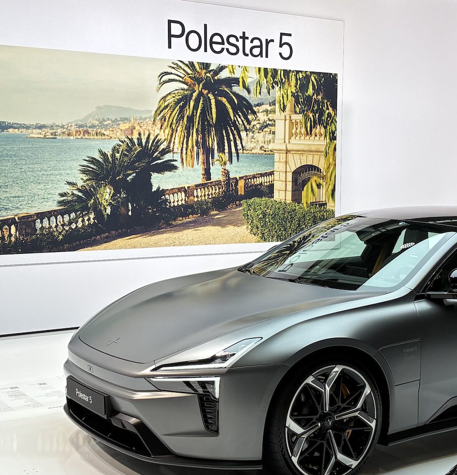 Grey Polestar 5GT in front of tropical depicted scene on a poster.