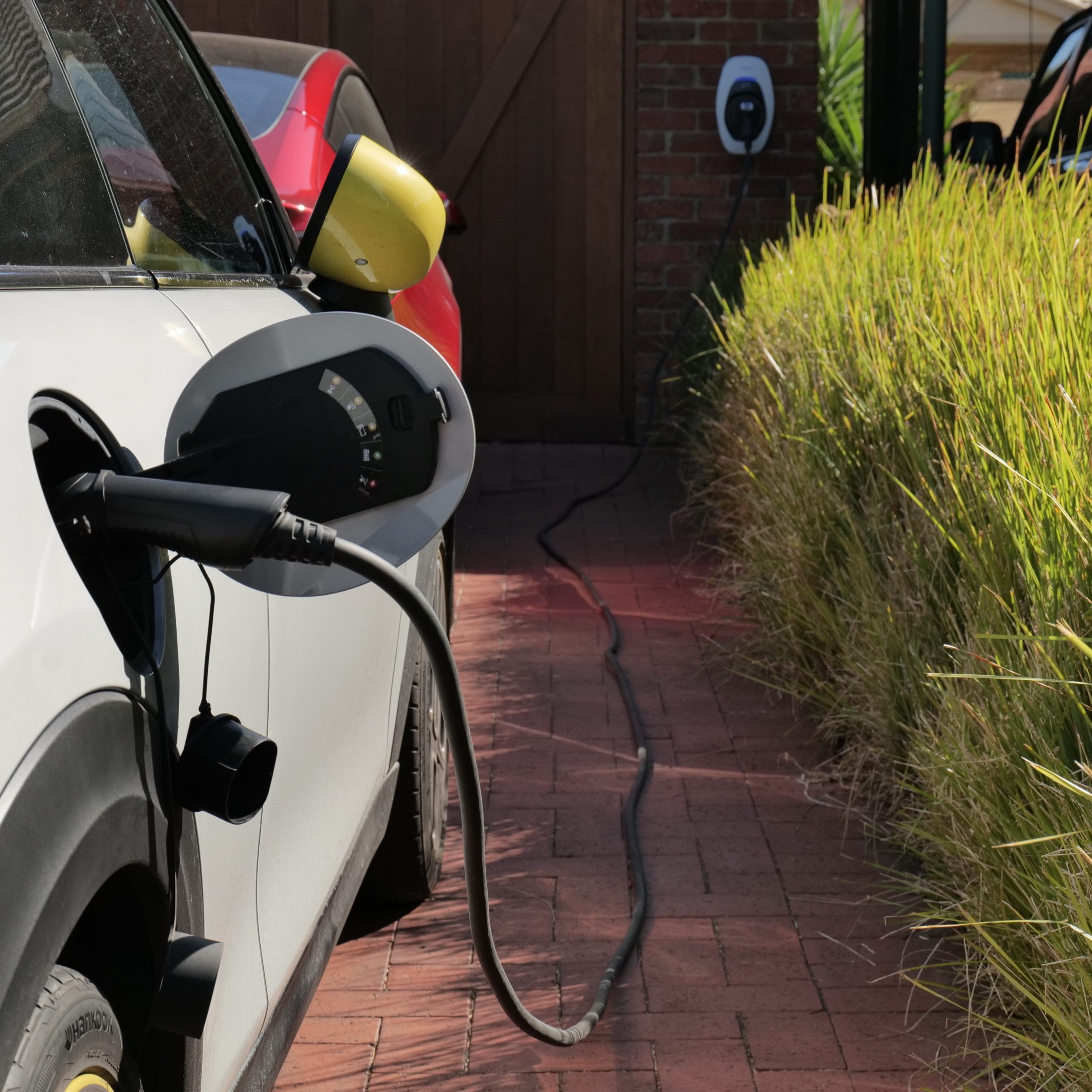 A car charging in a driveway with a long Type2-Type2 cable