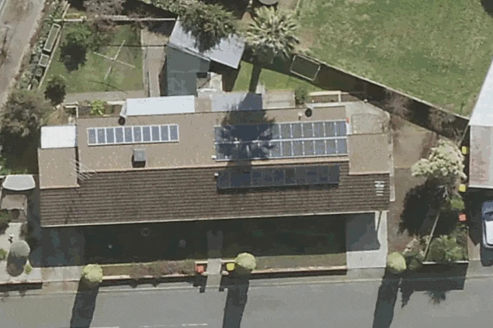 A big tree casts a shadow across a roof, affecting the output of the solar system.