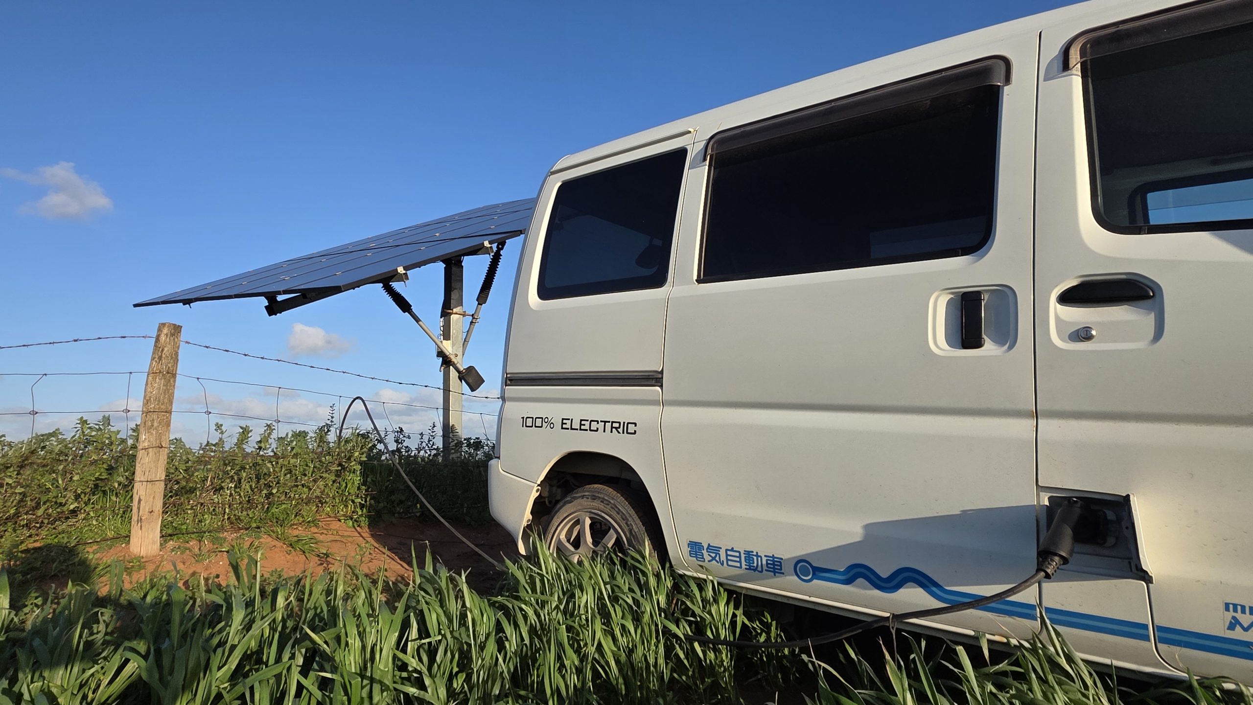 A cable plugged into an EV near a solar panel.